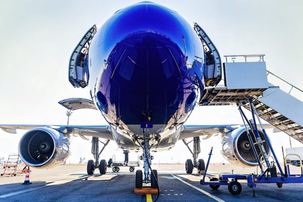 Fueling and final checking aircraft before taking off Fueling and final checking aircraft before taking off, view of open doors, turbines and boarding stairs, plane landing gear